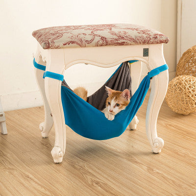 Cat lying in a blue hammock under a stool